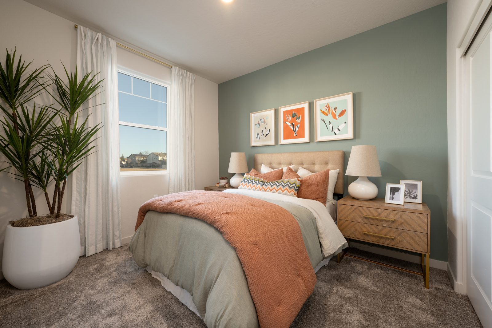 A bedroom with a bed and a plant.