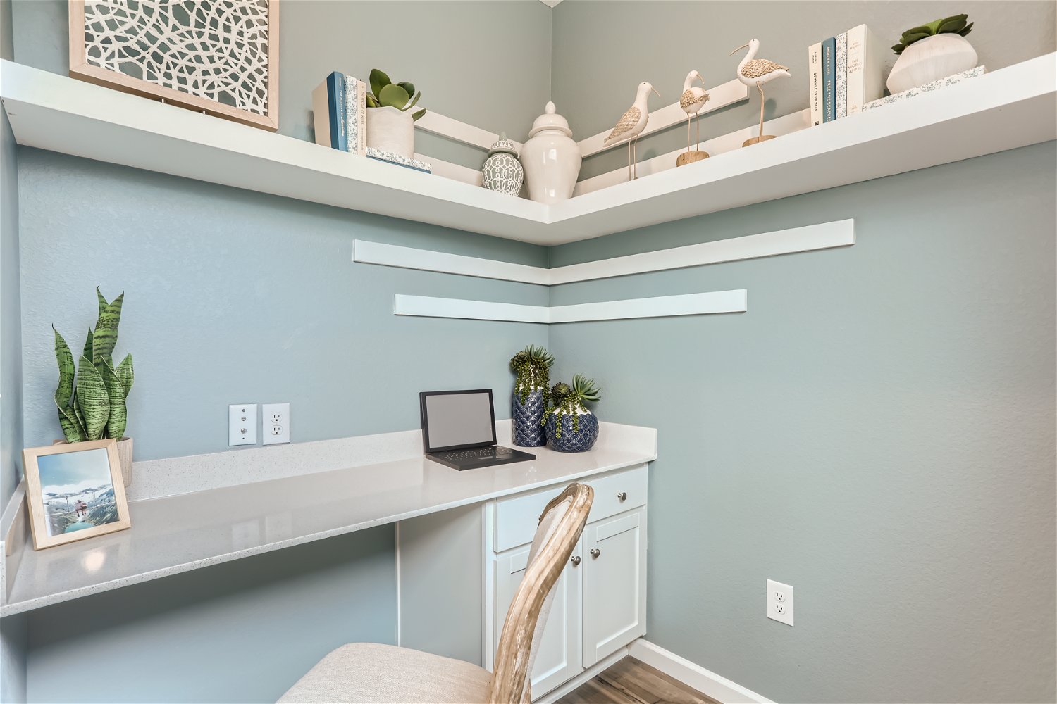 A white desk with a laptop and a chair in a room with white walls.