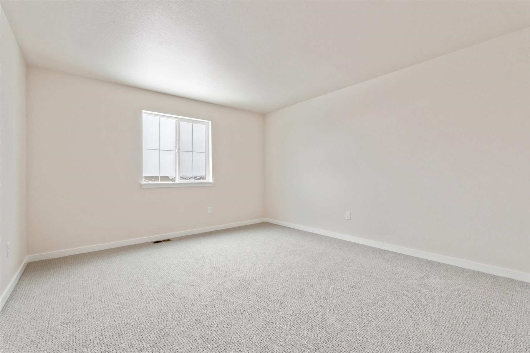 A room with a window and a white wall.