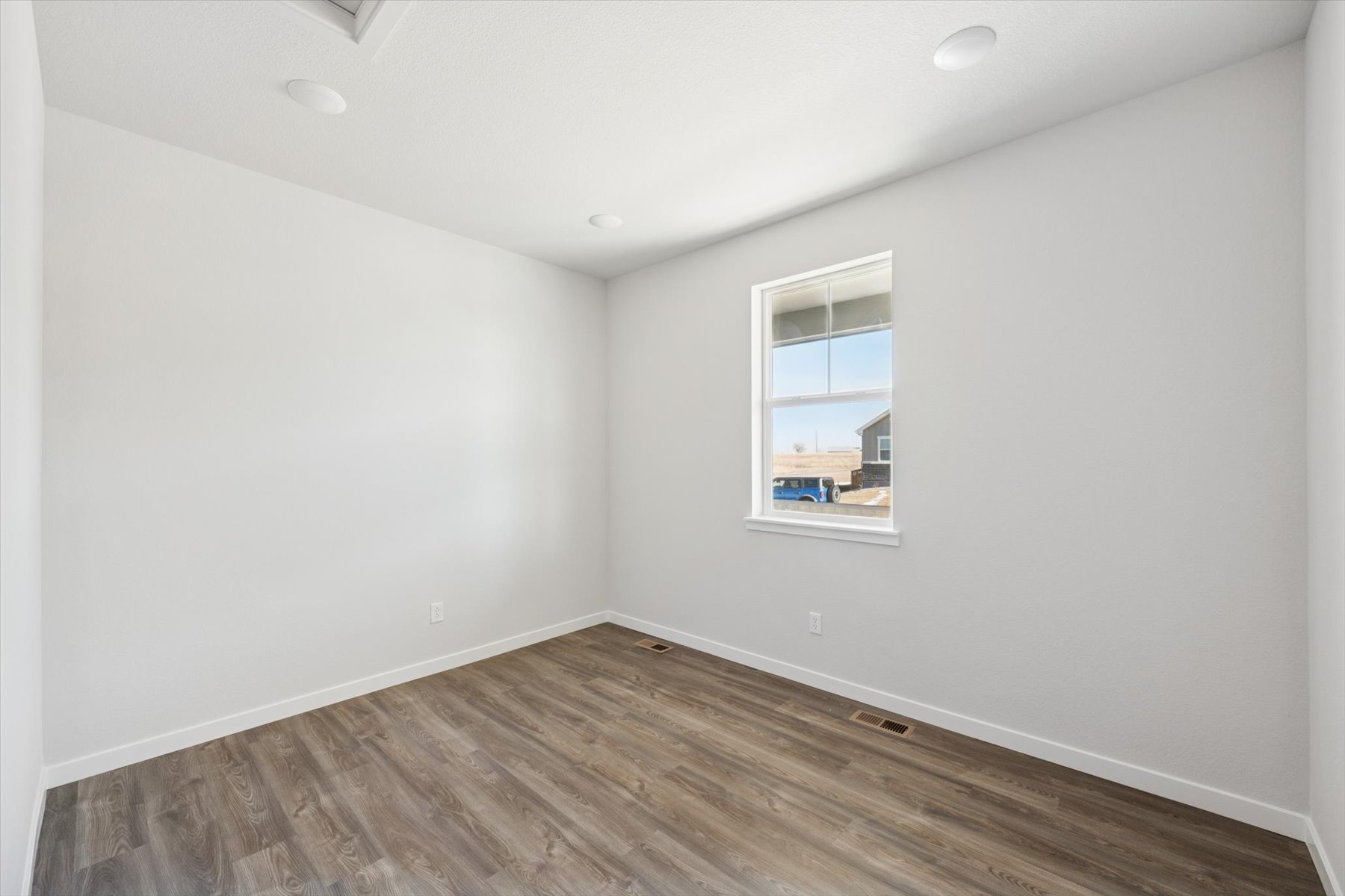 A room with a wood floor and a window.