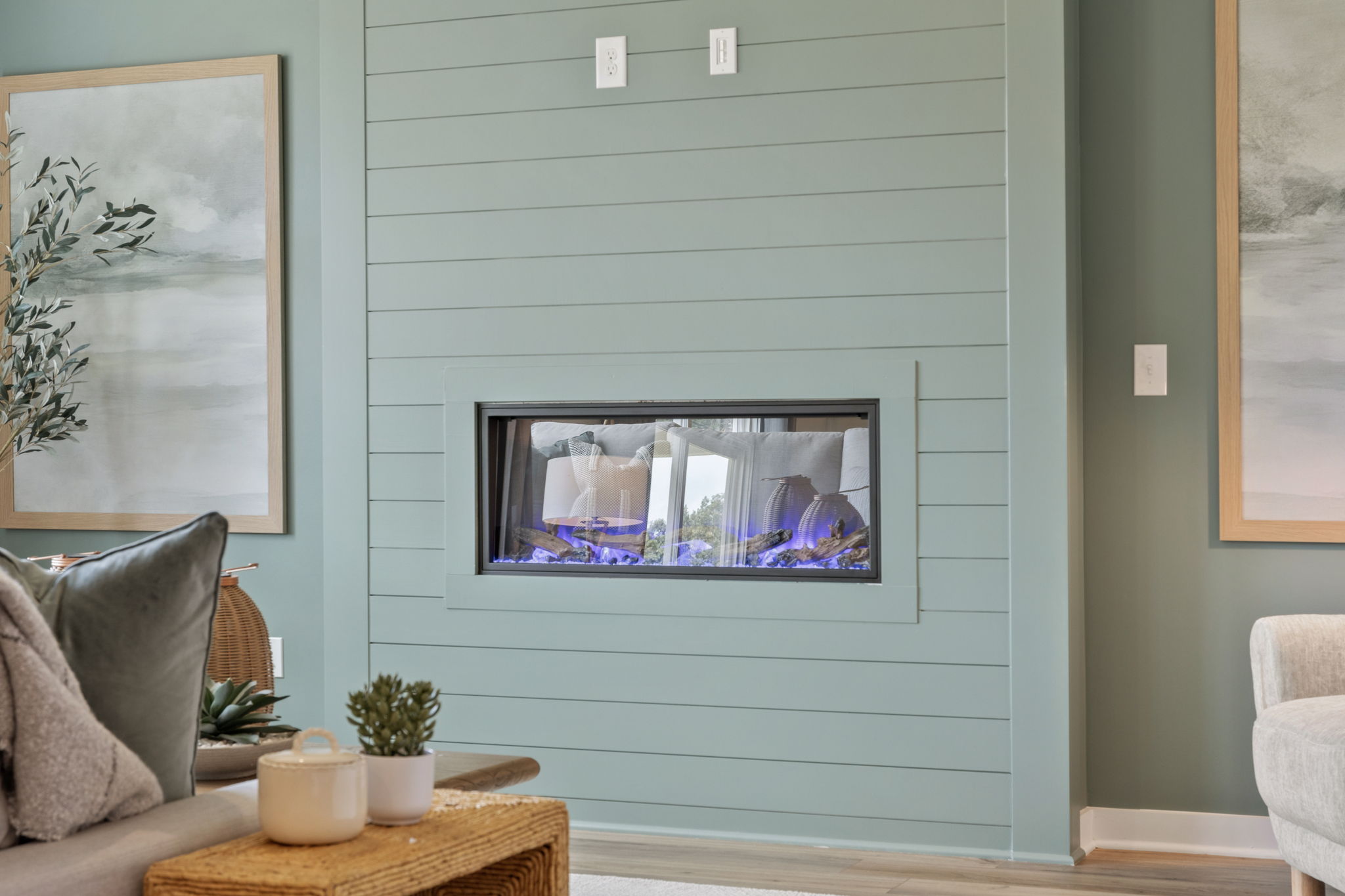 A room with a television and a table with a plant and a chair.