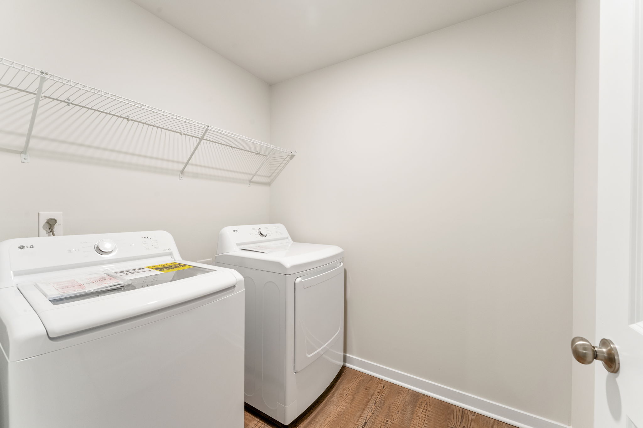 A white laundry room with a white wall and a white door.