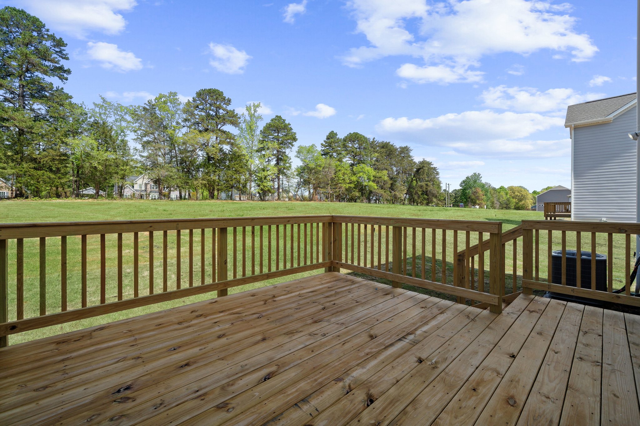 A wooden deck with a fence and trees in the background.