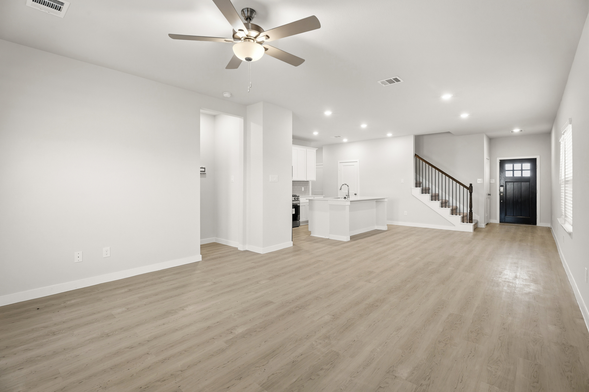 A large empty room with a wood floor and a white table.