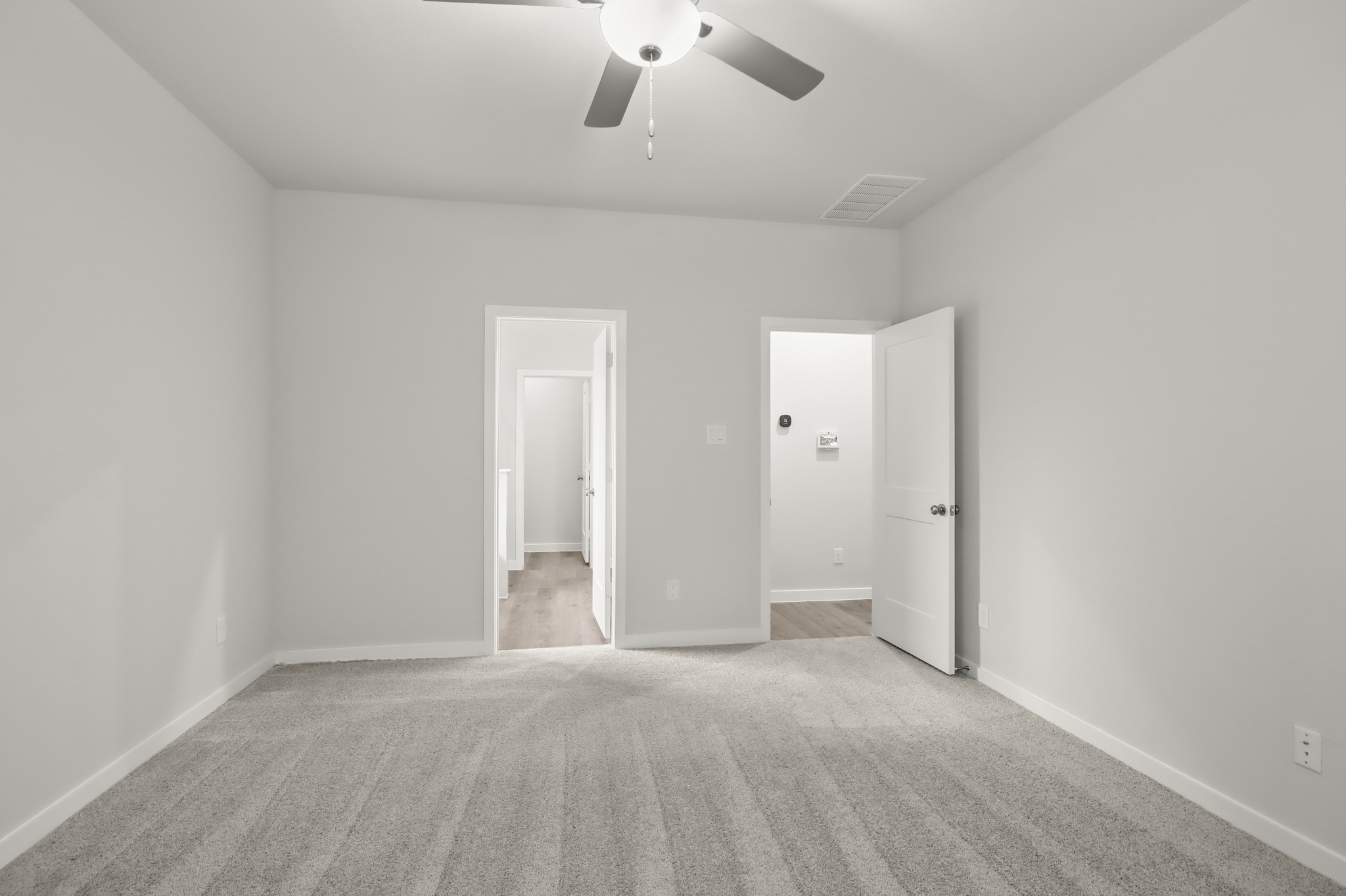 A room with a ceiling fan and a door.