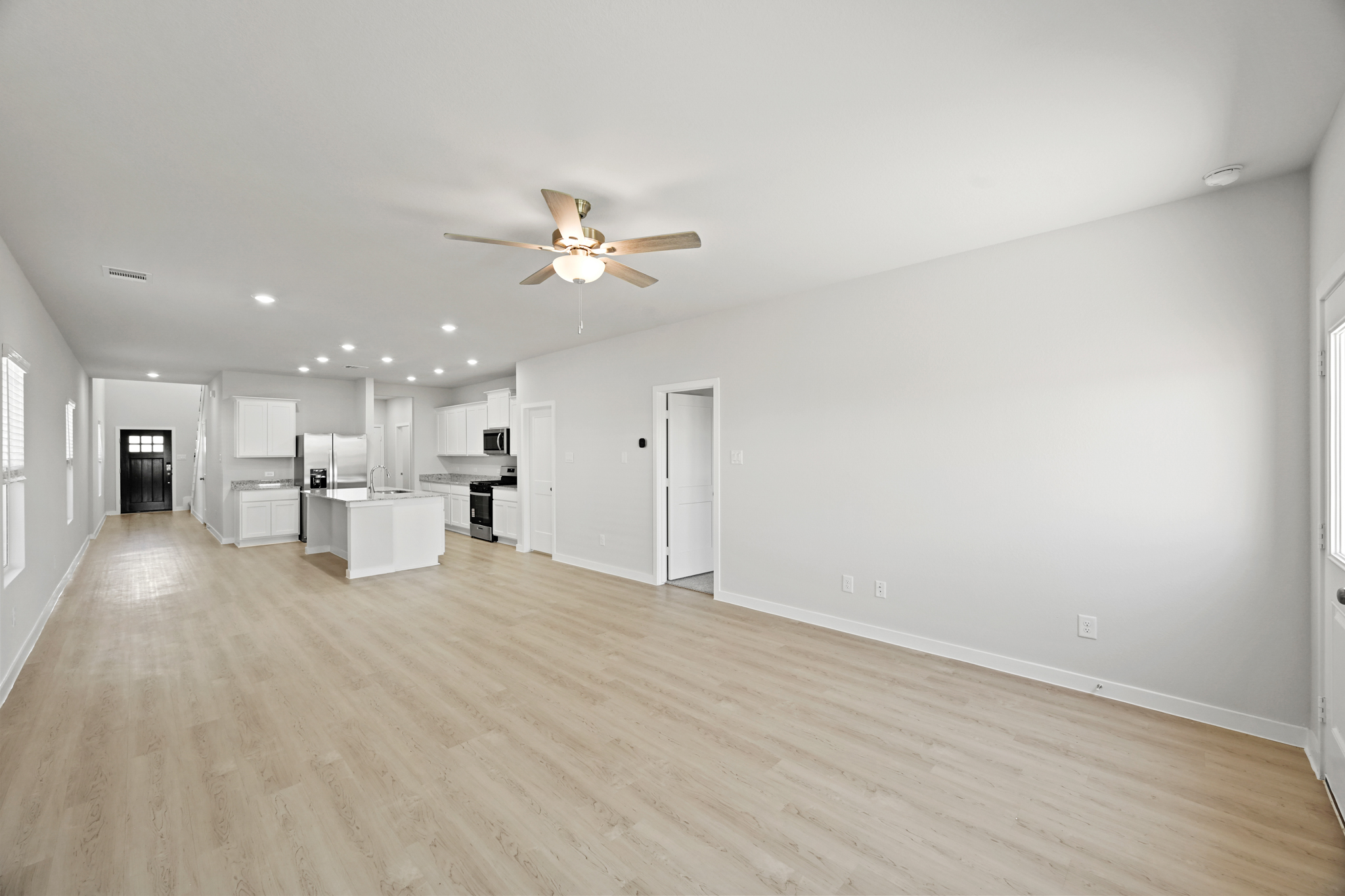 A large empty room with a ceiling fan and a wood floor.