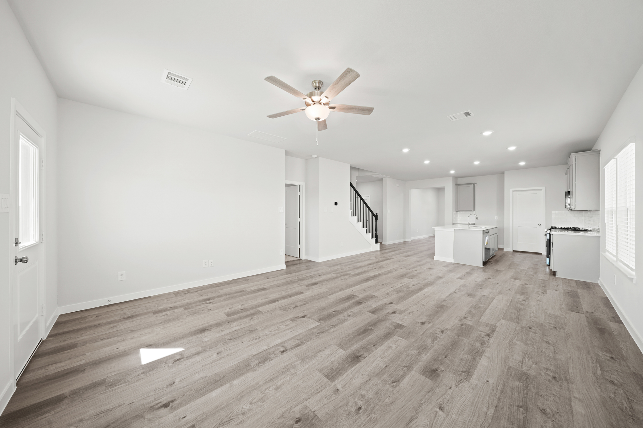 A large empty room with a wood floor and a ceiling fan.