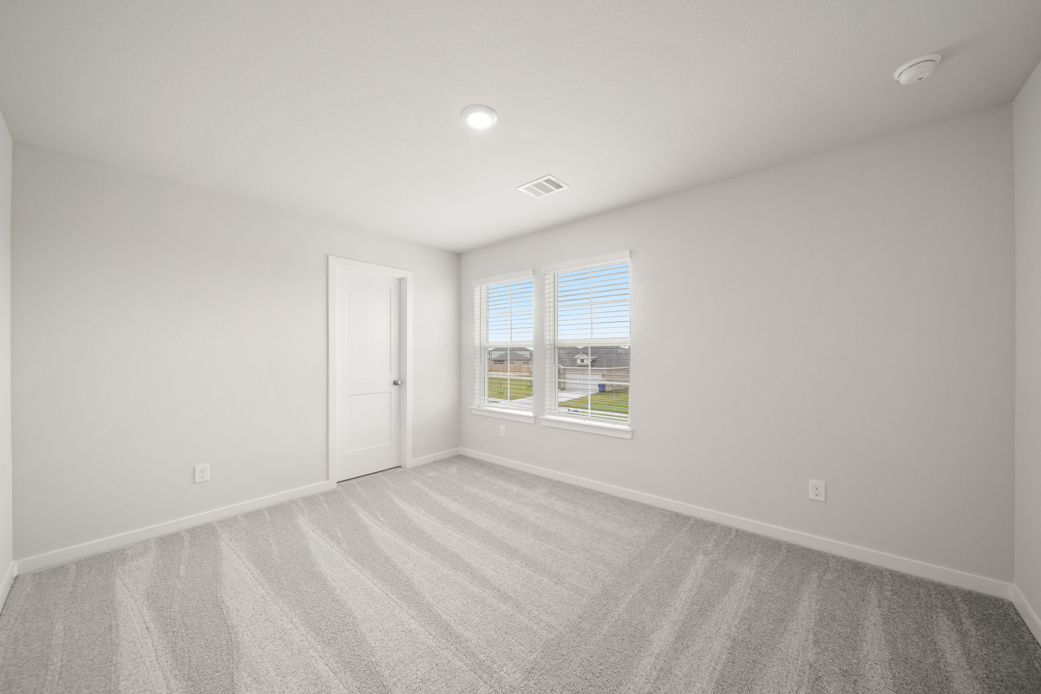 A room with a white carpet and a window.