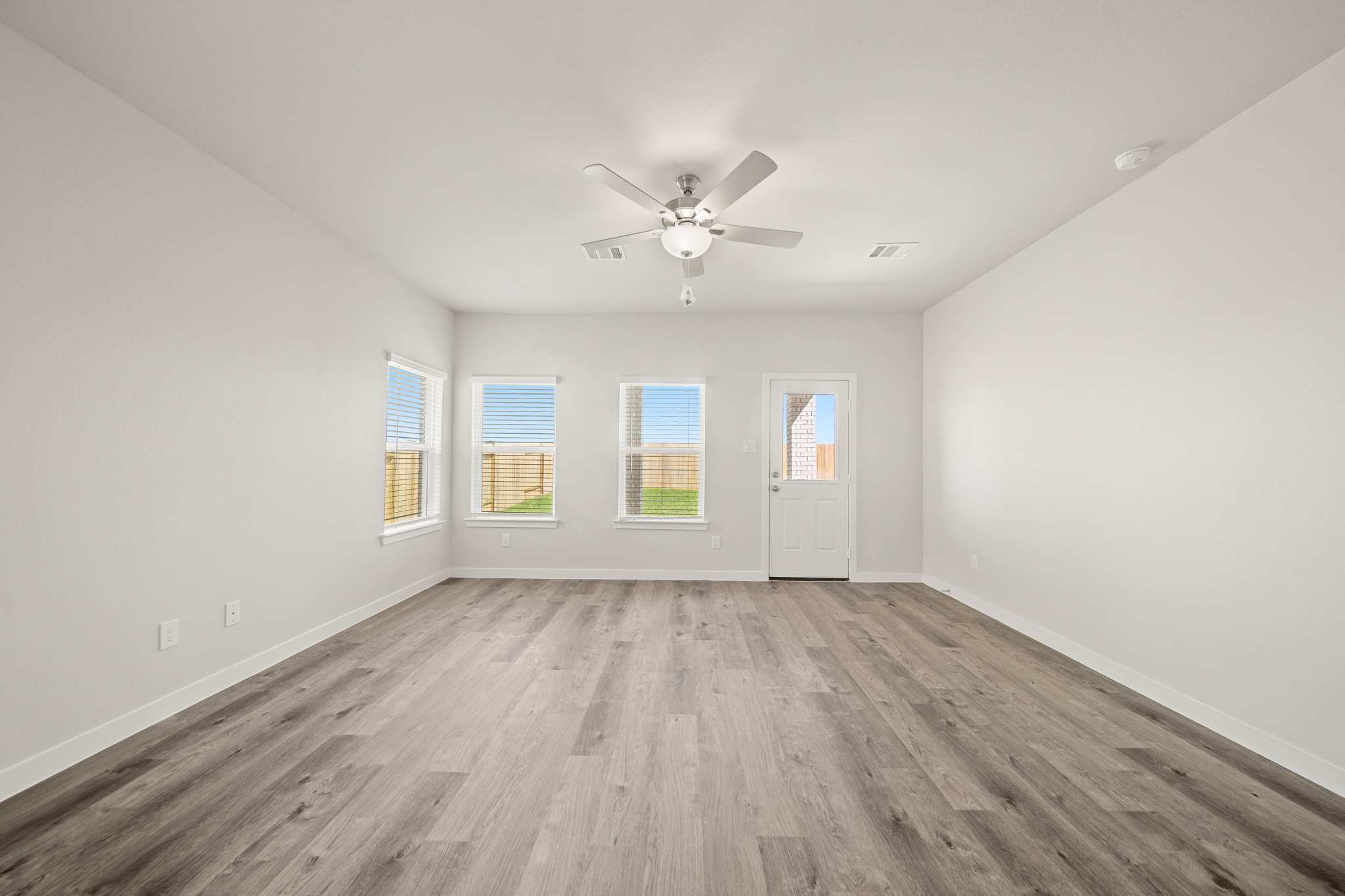A room with a ceiling fan and a wood floor.