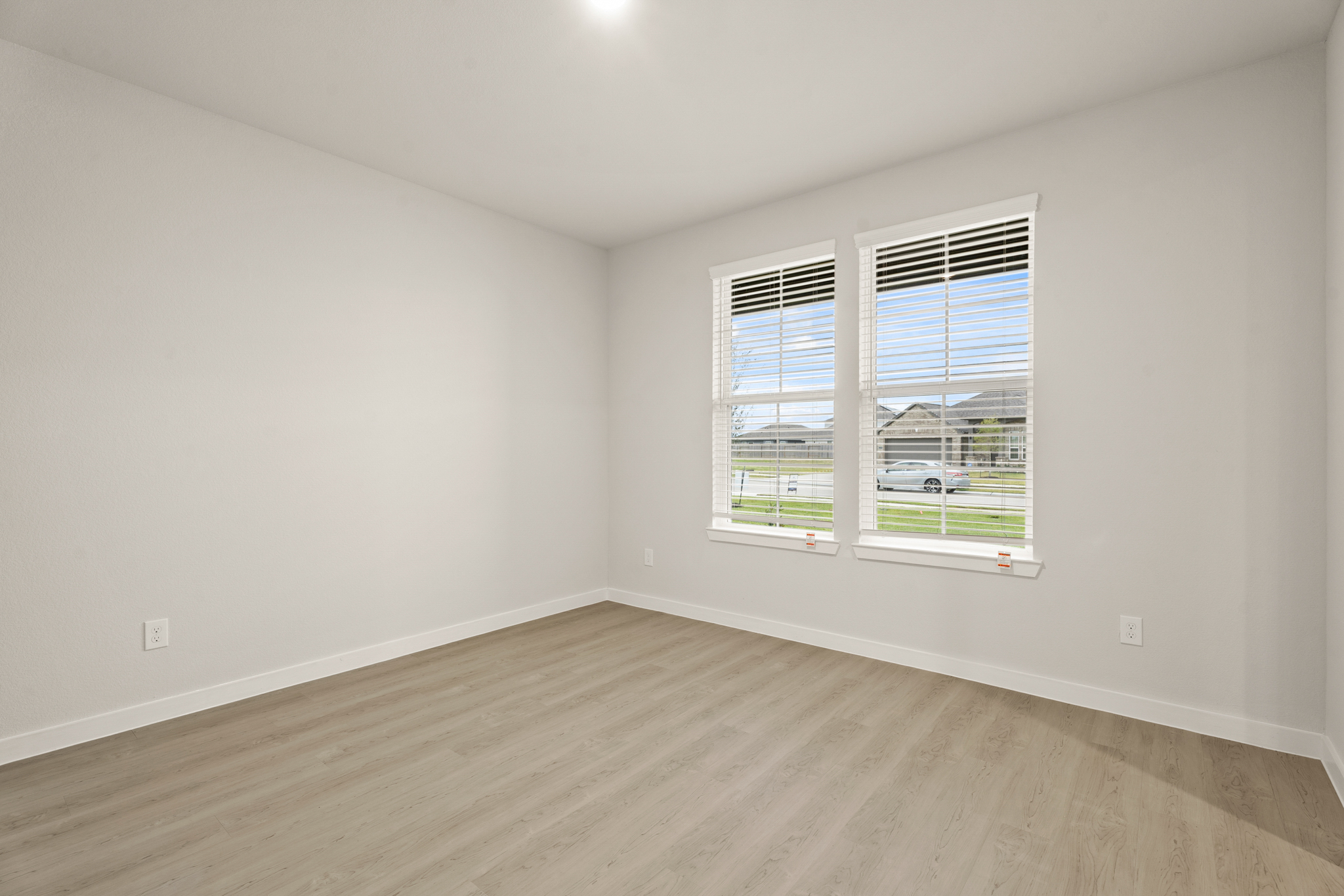 A room with a wood floor and a window with blinds.