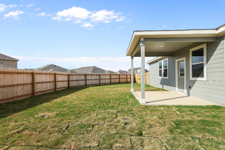A fenced in yard with a house and a wood fence.