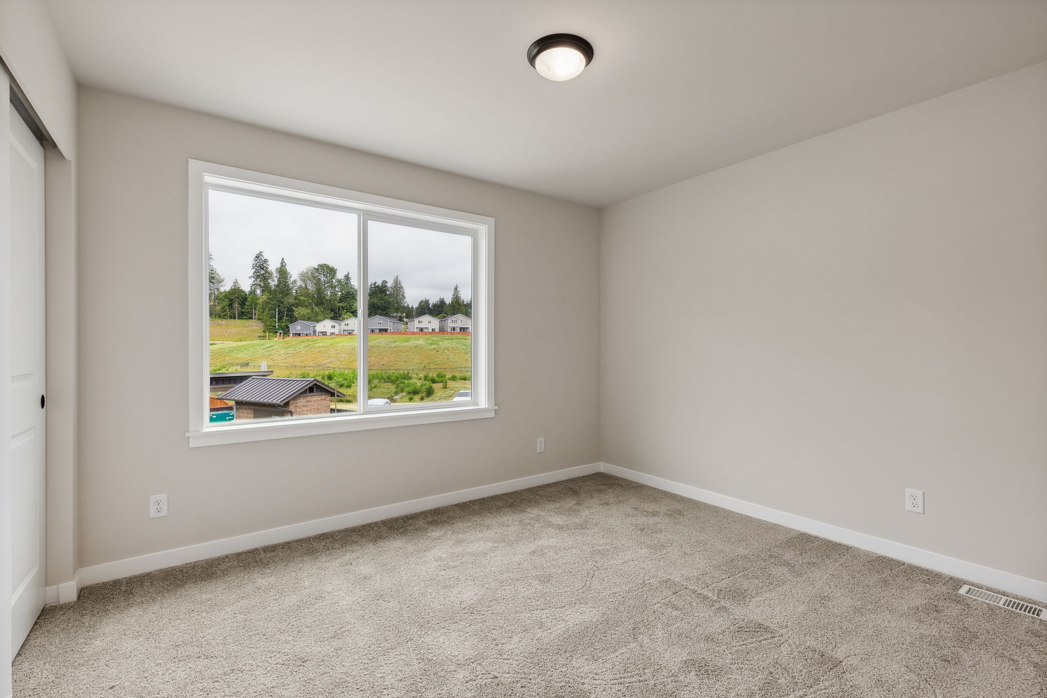 A room with a window and a view of a field.