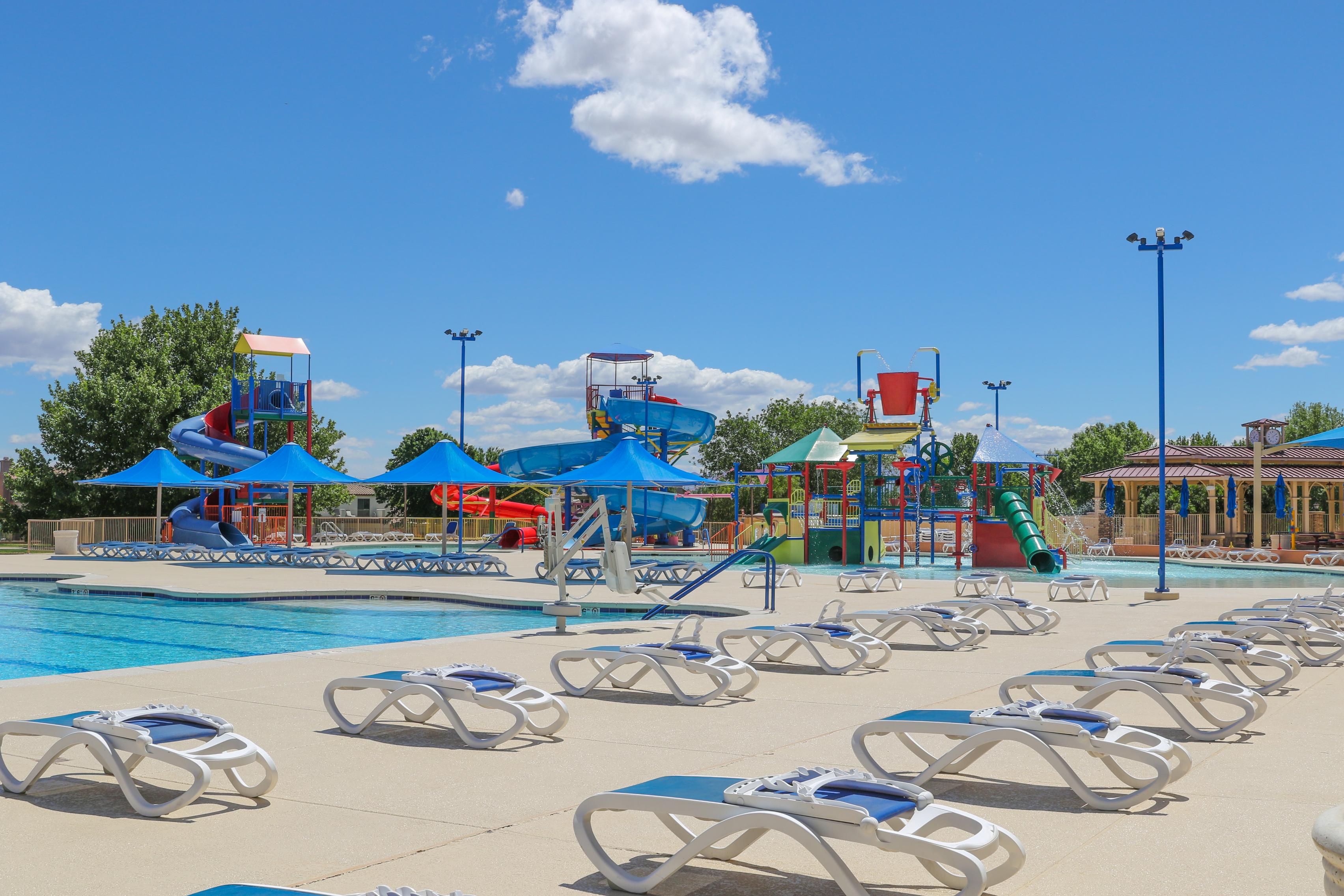 A pool with lounge chairs and a slide.